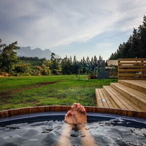 Ein Whirlpool mit Blick auf ein Wiesfeld und Berge im Hintergrund.