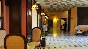 A hotel corridor with patterned flooring, wooden chairs, and a decorative ceiling. - Dar Ismail Nour Elain (Ain Draham)