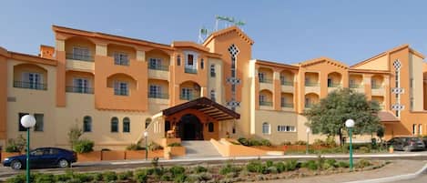 A multi-story hotel with a central courtyard, balconies, and a prominent entrance with steps.