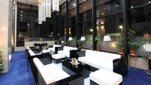 Eine moderne Lobby mit weißen Sofas, schwarzen Couchtischen und Topfpflanzen.