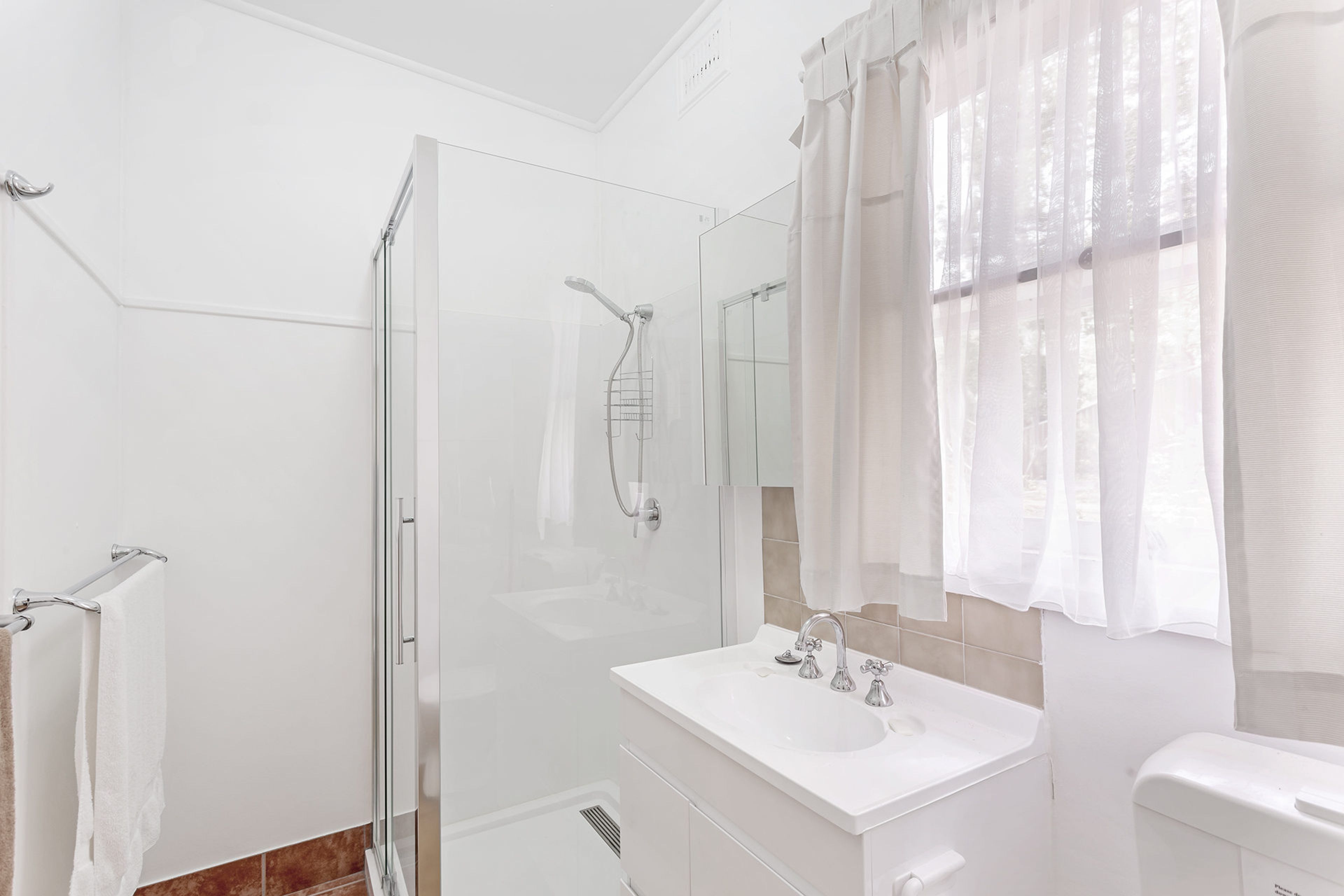 A modern bathroom with a glass-enclosed shower, a white vanity with a mirror, and a toilet.