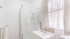 Een moderne badkamer met een douchecabine van glas, een witte wastafel met spiegel en een toilet.