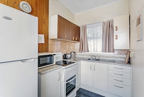 Een kleine keuken met een koelkast, magnetron, broodrooster, oven en een spoelbak.