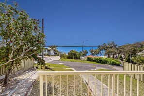 A residential area with a clear view of the ocean, a curved road, and a fenced property.
