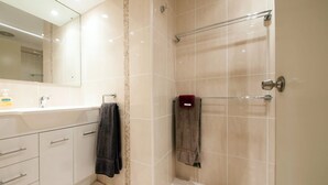 Un baño moderno con ducha, lavamanos y espejo.