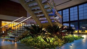 A spacious indoor area with a prominent staircase, large windows, and a well-lit atrium with plants. - Hotel Suigekka (Wakasa)