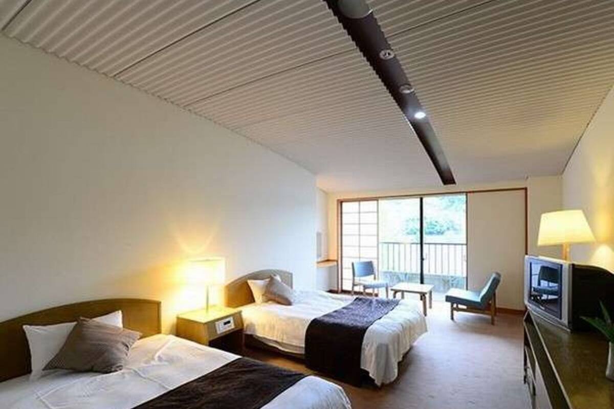 A hotel room with two beds, a television, a desk, and a chair.
