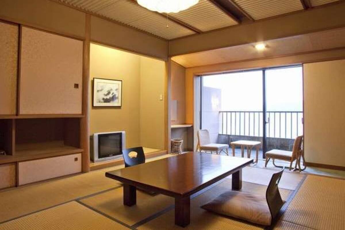 A traditional Japanese room with tatami flooring, a low table, and a television.