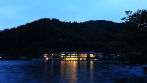 A waterfront hotel with multiple buildings, reflecting on the water, surrounded by a forested hillside. - Hotel Suigekka (Wakasa)
