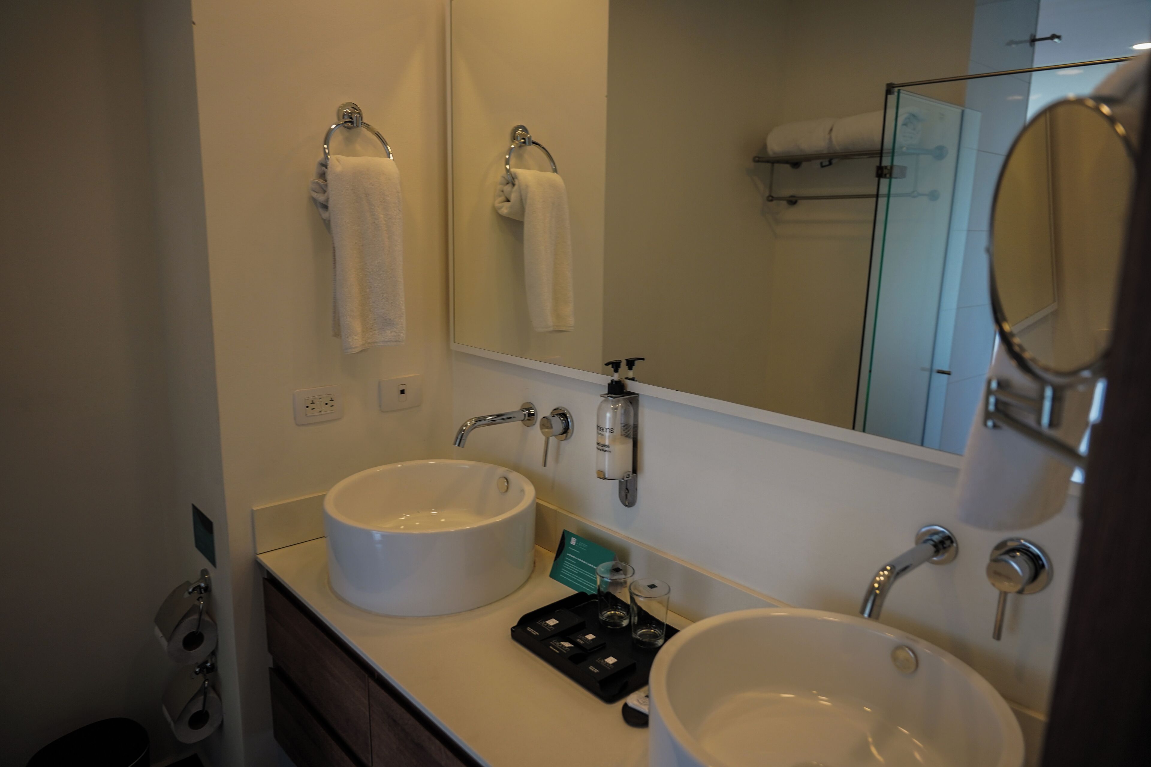 Un baño con dos lavamanos, un espejo y un perchero para toallas.