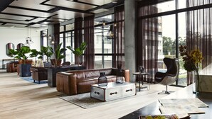A spacious living area with a leather sofa, a coffee table, and a large window with curtains. - Hotel Lagoon (Rionegro)
