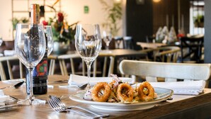 A dining table with a plate of food, wine glasses, and a bottle of wine. - Hotel Lagoon (Rionegro)