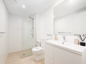 Une salle de bain moderne avec une douche à parois de verre, des toilettes et un meuble-lavabo avec un miroir.