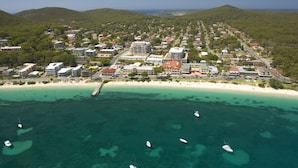 Ein Luftbild einer Küstenstadt mit Strand, klarem türkisblauem Wasser und mehreren Booten.