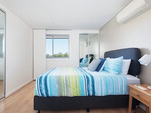 Een moderne slaapkamer met een bed, nachtkastje en raam.