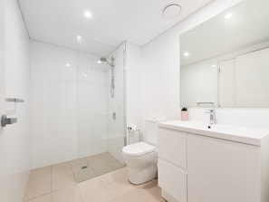 Een moderne badkamer met een douchecabine van glas, een wit toilet en een wastafel met spiegel.