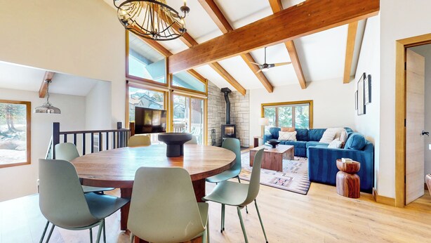 Een ruime kamer met een houten eettafel, stoelen, een blauwe bank en een stenen openhaard.