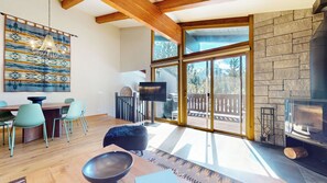 Ein modernes Wohnzimmer mit Kamin, großen Fenstern und einem Essbereich.