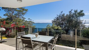An outdoor dining area with a table and chairs, overlooking a body of water and a mountainous landscape. - Mirage Holiday Home with Water Views Nelson Bay (Nelson Bay)