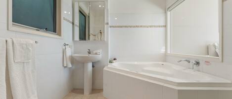 A modern bathroom with a bathtub, sink, and a large mirror.