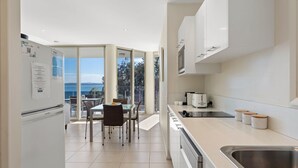 Une cuisine moderne avec vue sur la mer, un coin repas avec une table et des chaises, et un réfrigérateur.