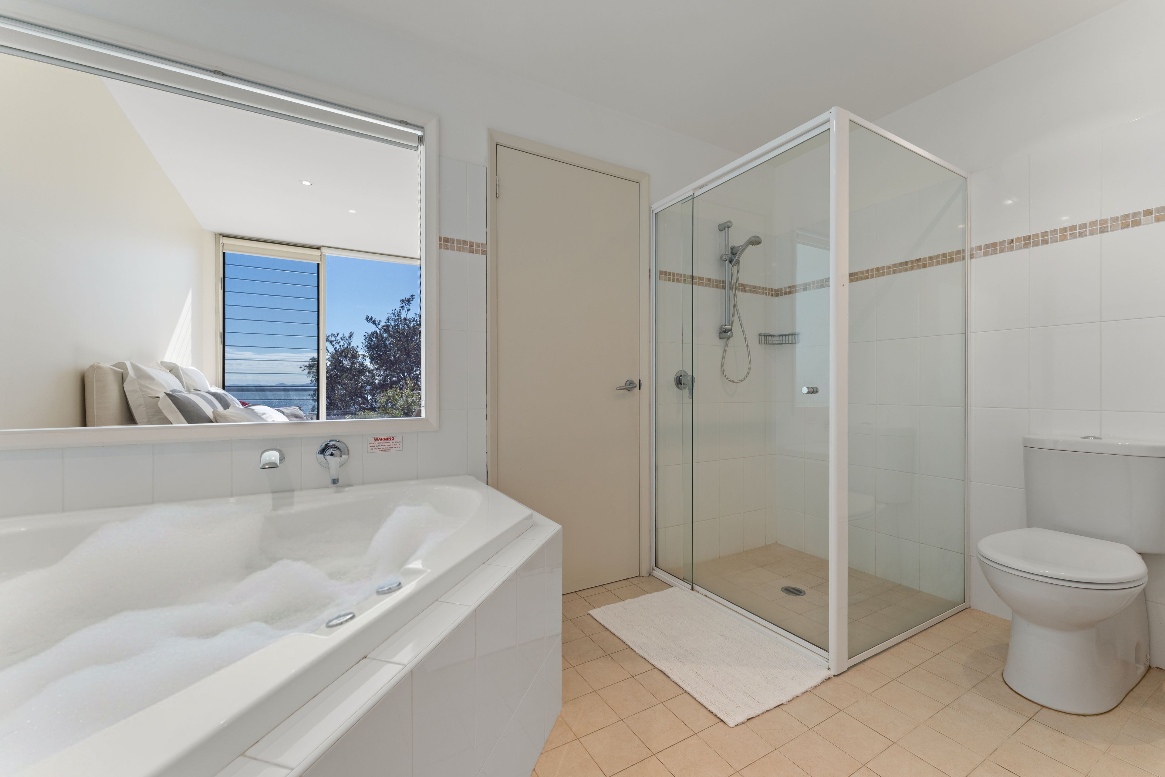 A bathroom with a bathtub, a glass-enclosed shower, and a toilet.