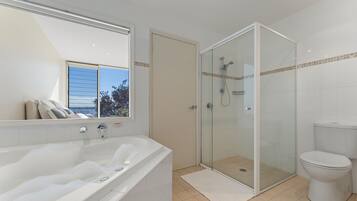 A bathroom with a bathtub, a glass-enclosed shower, and a toilet.
