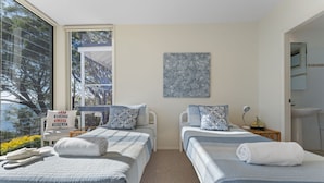 A hotel room with two beds, a large window with a view of trees, a painting on the wall, and a bathroom visible through an open door. - Mirage Holiday Home with Water Views Nelson Bay (Nelson Bay)