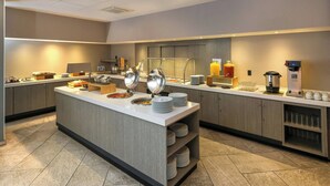 A modern hotel breakfast area with a central island, buffet setup, and coffee station. - City Express Plus by Marriott Tampico (Tampico)