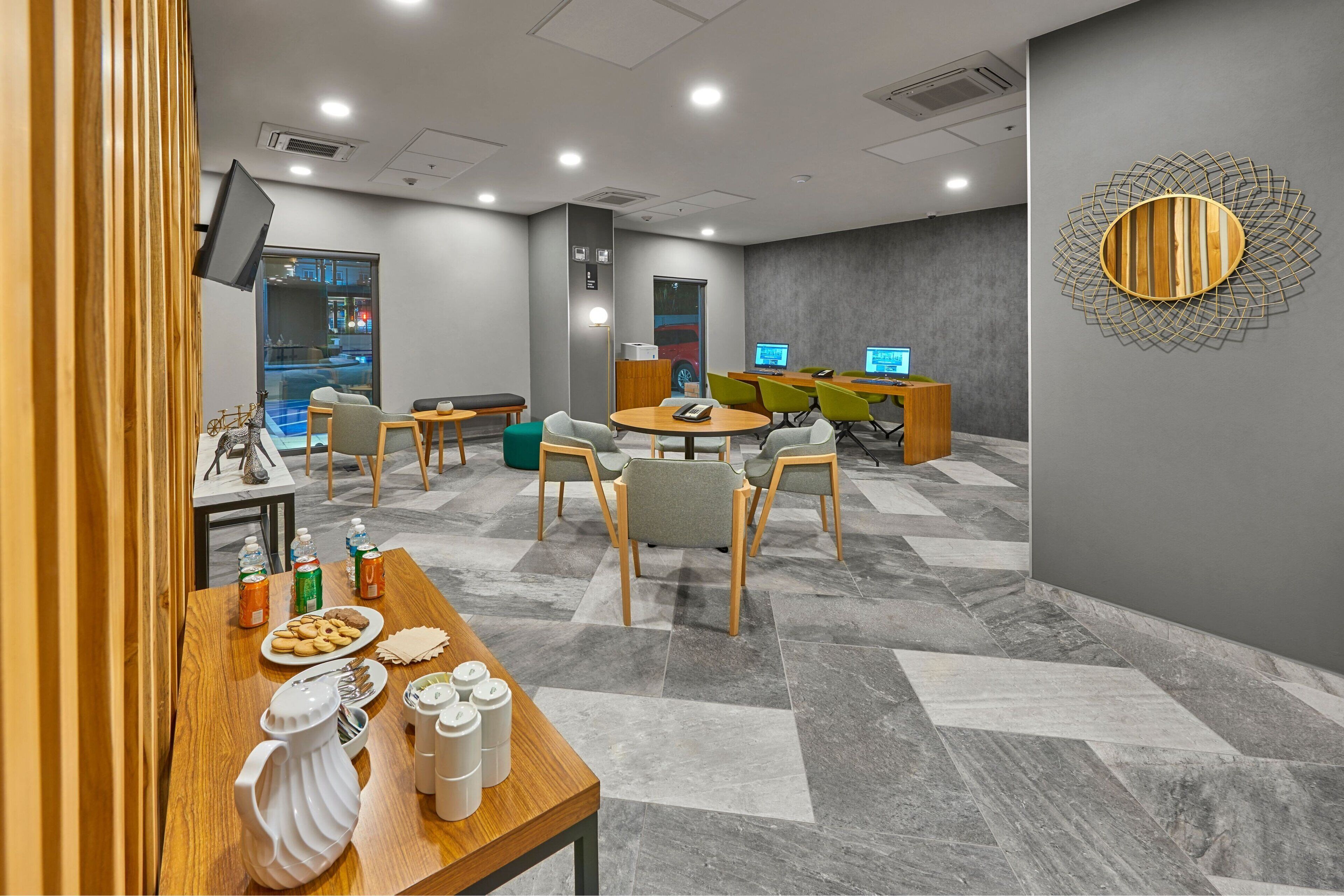 Un hall d’hôtel moderne avec une table ronde, des chaises et un comptoir d’accueil.