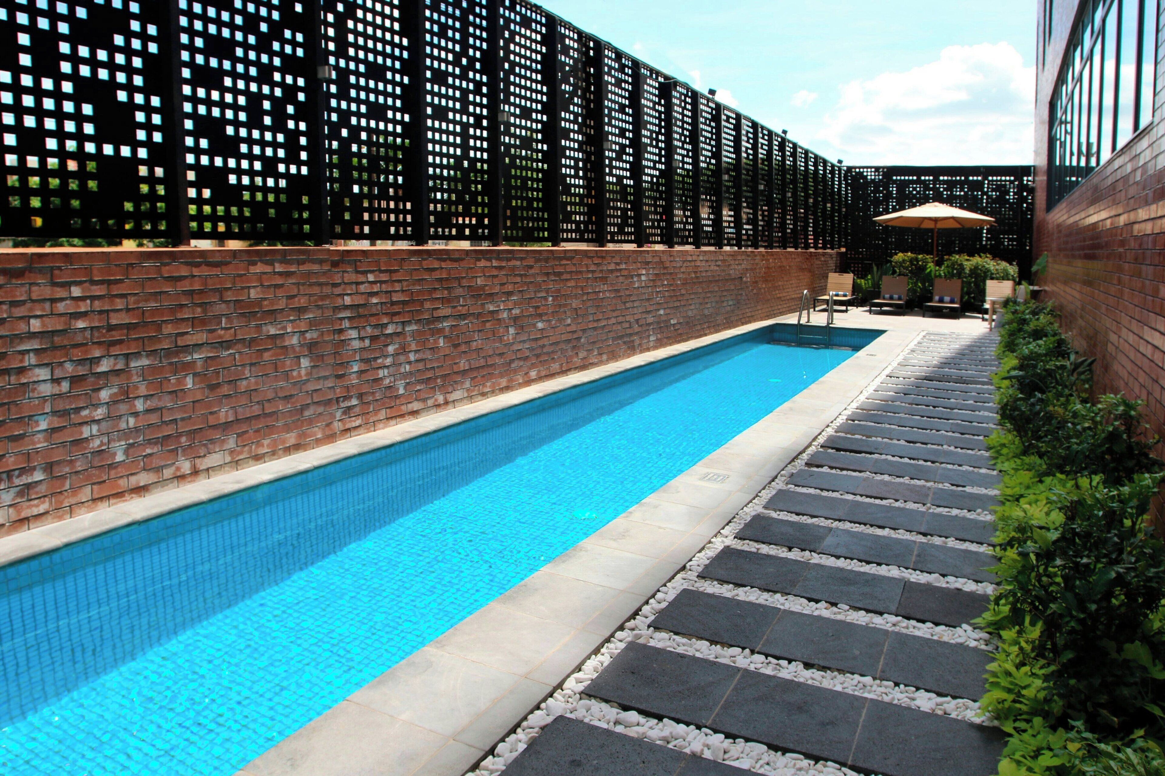 A swimming pool with a brick wall and a black fence.