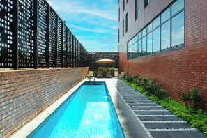 A swimming pool with a brick wall on one side and a glass building on the other.