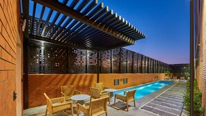 A poolside area with a pergola, seating, and a brick wall. - City Express Plus by Marriott Tampico (Tampico)