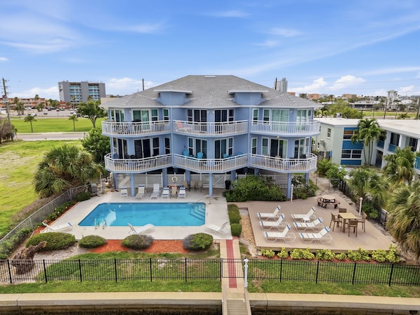 A multi-story building with balconies, a swimming pool, and outdoor seating areas.