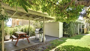 A covered outdoor area with a grill, a table, and a shed. - Florida Shoal Bay Townhouse near Beach (Shoal Bay)
