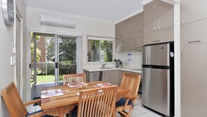 Una cocina moderna con una mesa de comedor, sillas, un refrigerador y un lavavajillas.