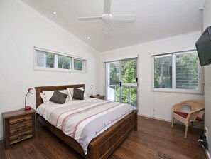 A bedroom with a wooden bed, a nightstand, a chair, and a ceiling fan.