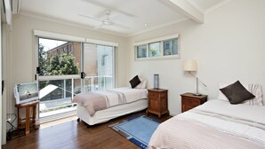 A bedroom with two beds, a ceiling fan, a TV, and a view of the outside. - Florida Shoal Bay Townhouse near Beach (Shoal Bay)