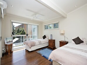 Een slaapkamer met twee bedden, een plafondventilator, een televisie en uitzicht op buiten.