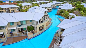 Ein Resort mit mehreren Gebäuden, einem zentralen Pool und umgebender Bepflanzung.