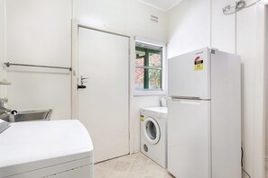 A laundry room with a washing machine, a dryer, and a refrigerator.