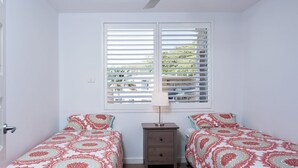 A bedroom with two single beds, a nightstand, and a window with blinds. - Del Rae, 18/25 Shoal Bay Rd - Air-conditioned, renovated 2-bedroom unit opposite Shoal Bay Beach (Shoal Bay)