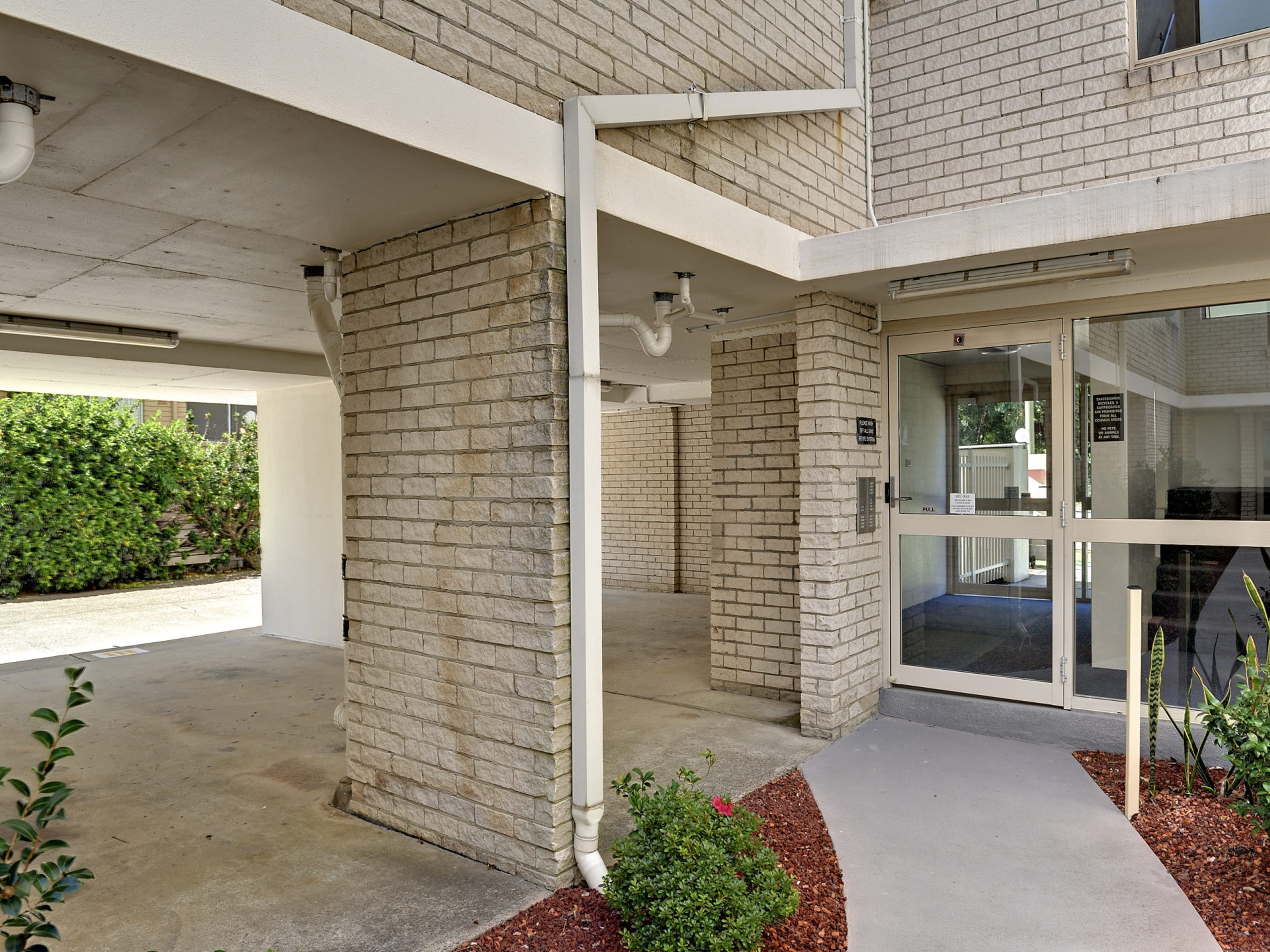 A building with a brick facade, a glass entrance, and a concrete floor.