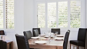 A dining area with a wooden table set for four, surrounded by black chairs. - Del Rae, 18/25 Shoal Bay Rd - Air-conditioned, renovated 2-bedroom unit opposite Shoal Bay Beach (Shoal Bay)