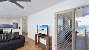 A modern living room with a TV, sofa, and wooden coffee table. - Del Rae, 18/25 Shoal Bay Rd - Air-conditioned, renovated 2-bedroom unit opposite Shoal Bay Beach (Shoal Bay)
