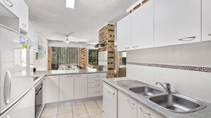 A modern kitchen with white cabinets, a granite countertop, and a brick accent wall.