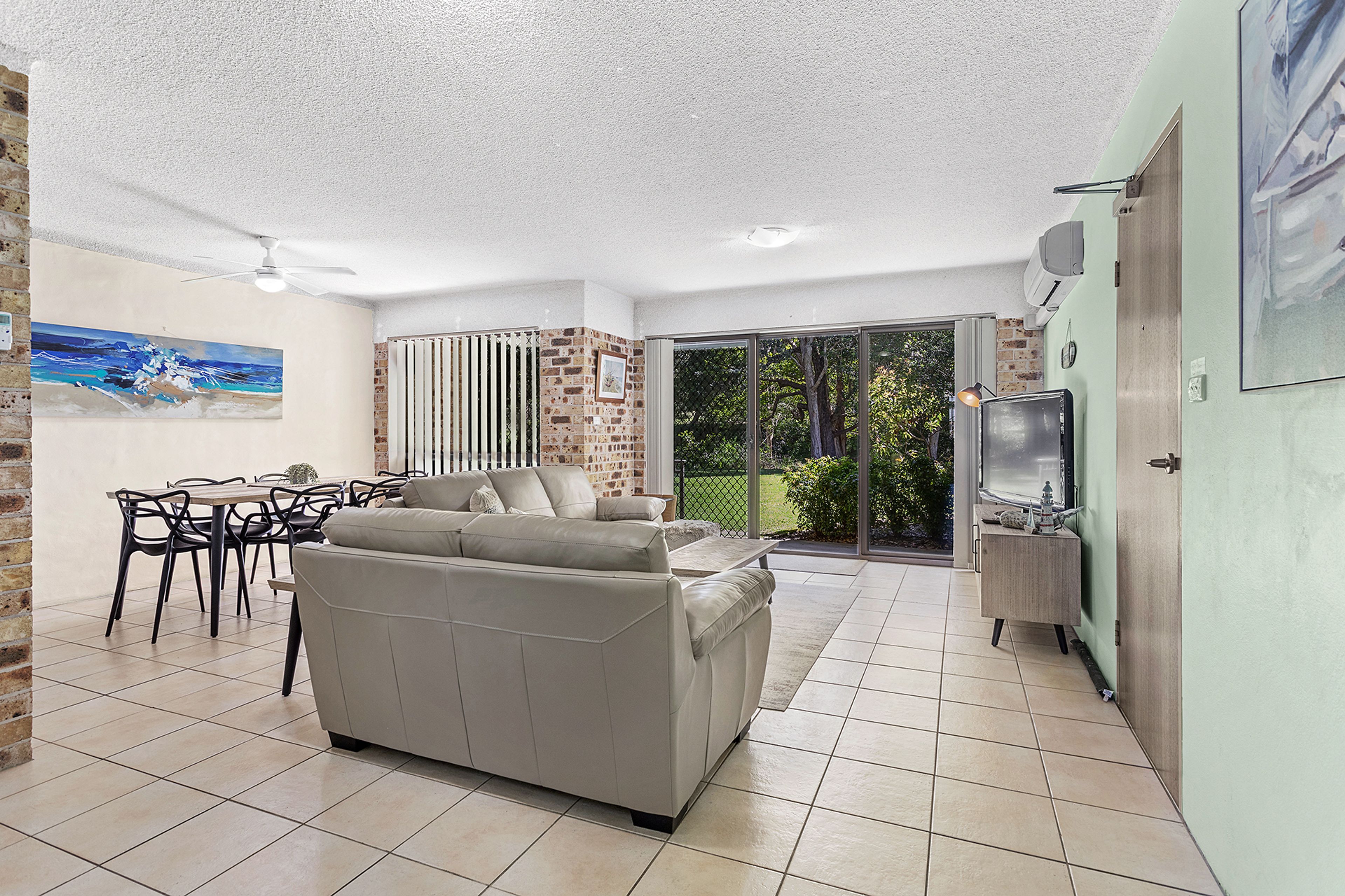 A living room with a sofa, dining table, chairs, and a TV.