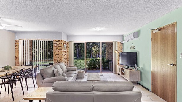 A modern living room with a sofa, TV, and dining area.
