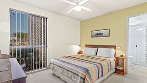 A bedroom with a bed, bedside lamps, a window with a view, and a ceiling fan.