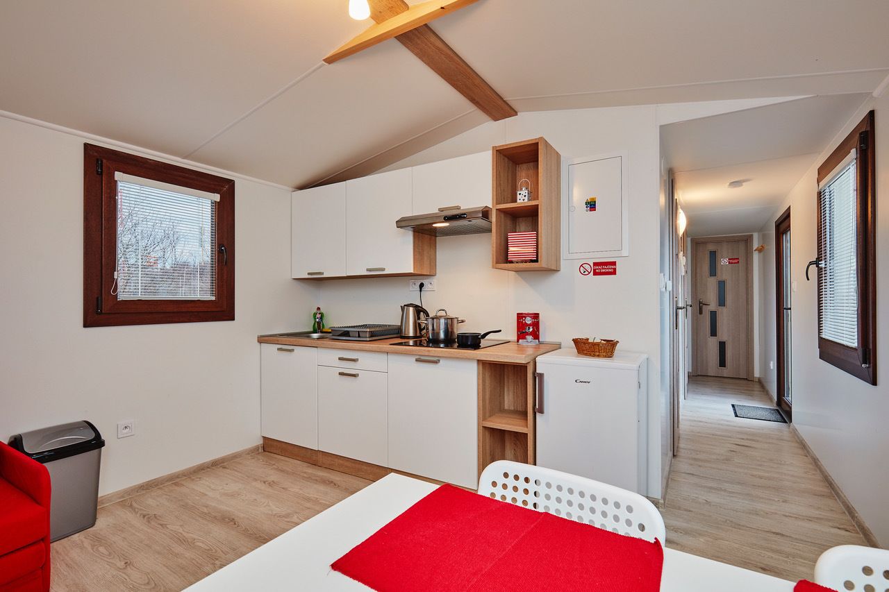 A compact kitchen with white cabinets, a wooden countertop, and a small refrigerator.